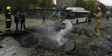 Bomberos y agentes de la policía trabajan en el sitio donde una explosión creó un cráter en una calle tras un ataque ruso en Dnipro, Ucrania. Foto: AP/Leo Correa