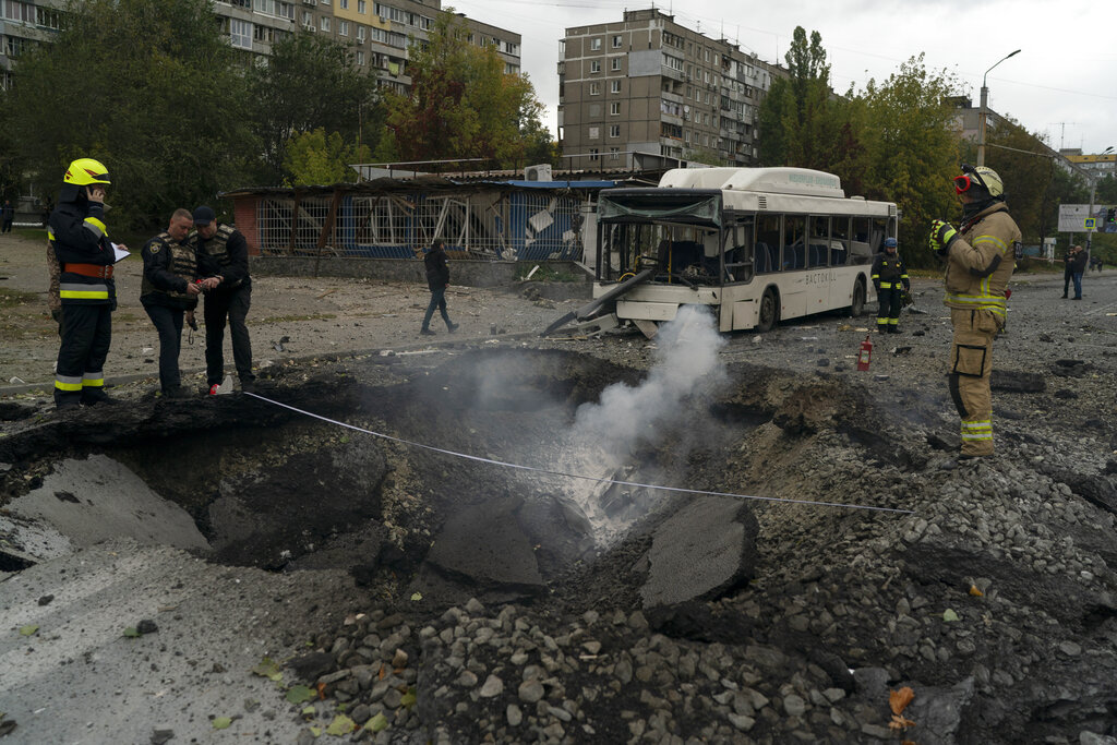 Bomberos y agentes de la policía trabajan en el sitio donde una explosión creó un cráter en una calle tras un ataque ruso en Dnipro, Ucrania. Foto: AP/Leo Correa