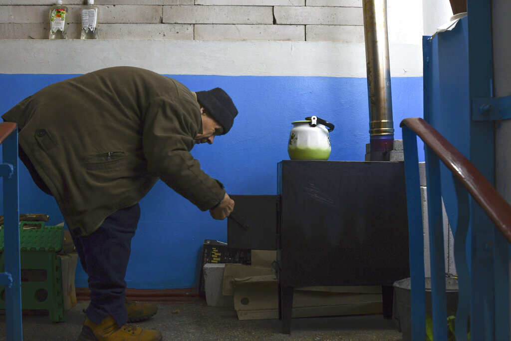 Un habitante junto a una estufa en Lyman, Donetsk, Ucrania, el 20 de noviembre de 2022. (Foto AP/Andriy Andriyenko)