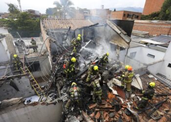 Bomberos trabajan en el lugar del accidente de una avioneta que cayó sobre casas en una zona residencial de Medellín, Colombia, el lunes 21 de noviembre de 2022. (AP Foto/Jaime Saldarriaga)