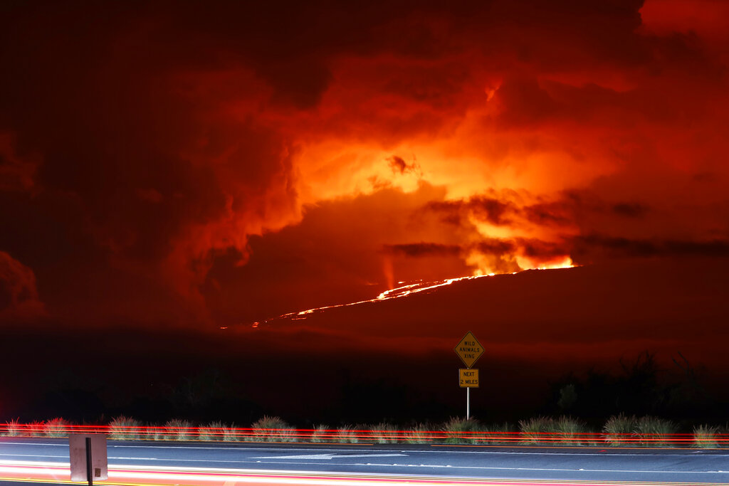 En esta fotogafía automóviles pasan frente al volcán Mauna Loa en erupción, el lunes 28 de noviembre de 2022, cerca de Hilo, Hawai. (AP Foto/Marco Garcia)