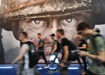 Visitantes pasan frente a un cartel publicitario del videojuego "Call of Duty" en la feria Gamescom en Colonia, Alemania, 22 de agosto de 2017. (AP Foto/Martin Meissner, Archivo)