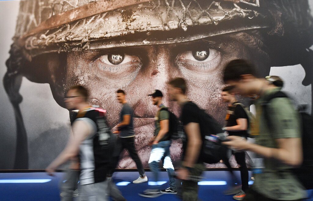 Visitantes pasan frente a un cartel publicitario del videojuego "Call of Duty" en la feria Gamescom en Colonia, Alemania, 22 de agosto de 2017. (AP Foto/Martin Meissner, Archivo)