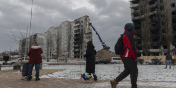 Residentes observan mientras un edificio atacado es desmantelado en Borodyanka, en la región de Kiev, Ucrania, el martes 13 de diciembre de 2022. (AP Foto/Andrew Kravchenko)