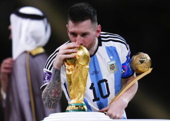 Lionel Messi besa el trofeo de la Copa del Mundo mientras sostiene el premio al mejor jugador del torneo tras la victorias 4-2 ante Francia por penales en la final, el domingo 18 de diciembre de 2022, en Lusail, Qatar. (AP Foto/Manu Fernández)