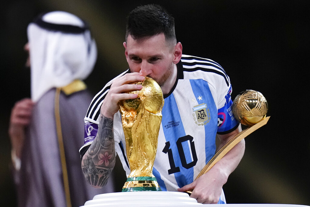 Lionel Messi besa el trofeo de la Copa del Mundo mientras sostiene el premio al mejor jugador del torneo tras la victorias 4-2 ante Francia por penales en la final, el domingo 18 de diciembre de 2022, en Lusail, Qatar. (AP Foto/Manu Fernández)