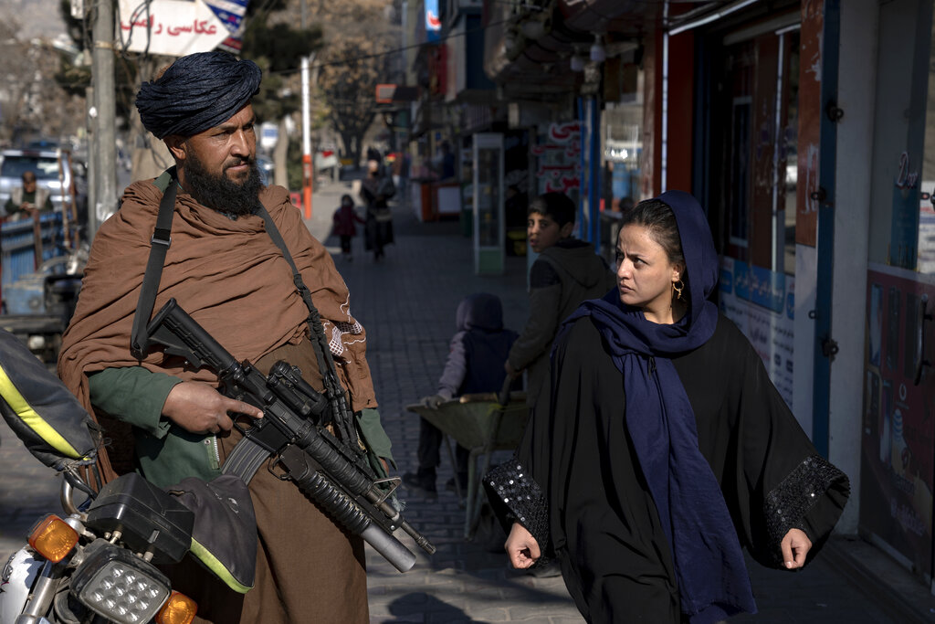 Una mujer pasa al lado de un guardia talibán en Kabul, Afganistán el 26 de diciembre de 2022.  (Foto AP/Ebrahim Noroozi)