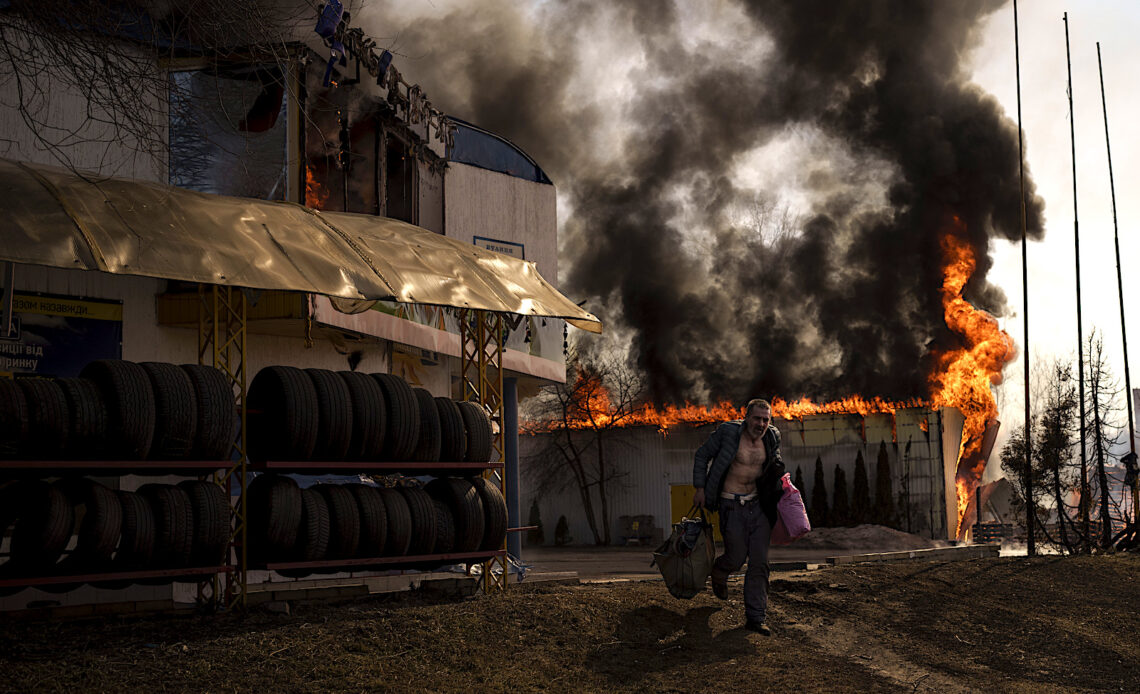Un hombre corre luego de recuperar artículos de una tienda en llamas tras un ataque ruso en Járkiv, Ucrania. (Foto: Felipe Dana | AP)