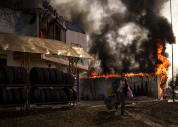 Un hombre corre luego de recuperar artículos de una tienda en llamas tras un ataque ruso en Járkiv, Ucrania. (Foto: Felipe Dana | AP)