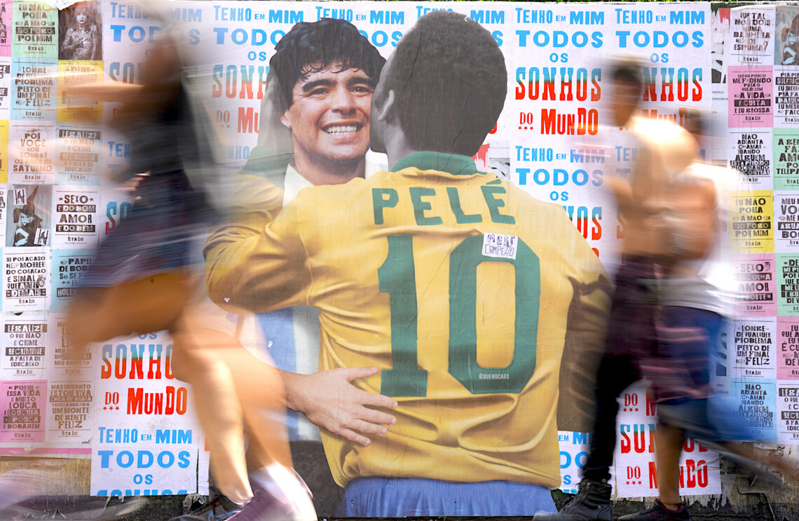 La gente pasa frente a un cartel que muestra al brasileño Pelé y al argentino Diego Maradona en Sao Paulo. (Foto: Andre Penner | AP)