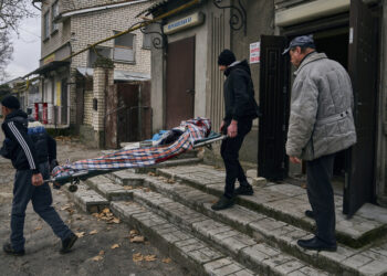 Civiles ucranianos cargan el cuerpo de un hombre de 20 años que murió en un bombardeo ruso en Jersón, Ucrania, el jueves 5 de enero de 2023. (Foto AP/LIBKOS)