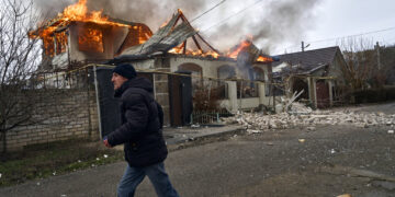 Un residente pasa junto a una casa en llamas tras un bombardeo ruso en Jersón, Ucrania, en la Nochebuena ortodoxa, el 6 de enero de 2023. (AP Foto/LIBKOS)
