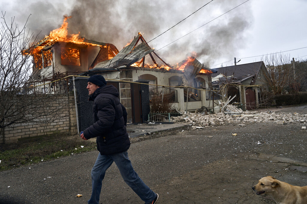 Un residente pasa junto a una casa en llamas tras un bombardeo ruso en Jersón, Ucrania, en la Nochebuena ortodoxa, el 6 de enero de 2023. (AP Foto/LIBKOS)