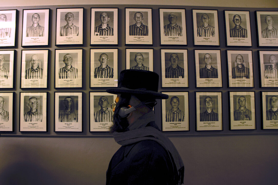 Un judío ortodoxo pasa por delante de los retratos de las víctimas del antiguo campo de concentración y extermino nazi de Auschwitz-Birkenau en Oswiecim, Polonia. (Foto: Michal Dyjuk | AP)
