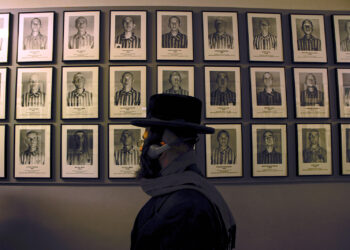 Un judío ortodoxo pasa por delante de los retratos de las víctimas del antiguo campo de concentración y extermino nazi de Auschwitz-Birkenau en Oswiecim, Polonia. (Foto: Michal Dyjuk | AP)