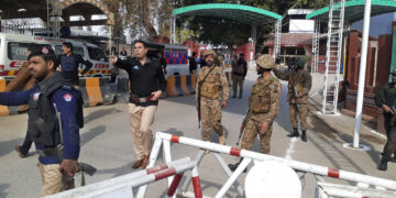 Soldados y policías despejan el acceso para ambulancias al lugar donde explotó una bomba, en una entrada a oficinas policiales en Peshawar, Pakistán, el lunes 30 de enero de 2023. (AP Foto/Muhammad Sajjad)