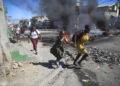 Una mujer y su hija pasan corriendo frente a una barricada levantada por la policía en protesta por el mal gobierno policial en Puerto Príncipe, Haití, el 26 de enero de 2023. (Foto: AP/Odelyn Joseph, Archivo)