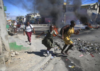 Una mujer y su hija pasan corriendo frente a una barricada levantada por la policía en protesta por el mal gobierno policial en Puerto Príncipe, Haití, el 26 de enero de 2023. (Foto: AP/Odelyn Joseph, Archivo)