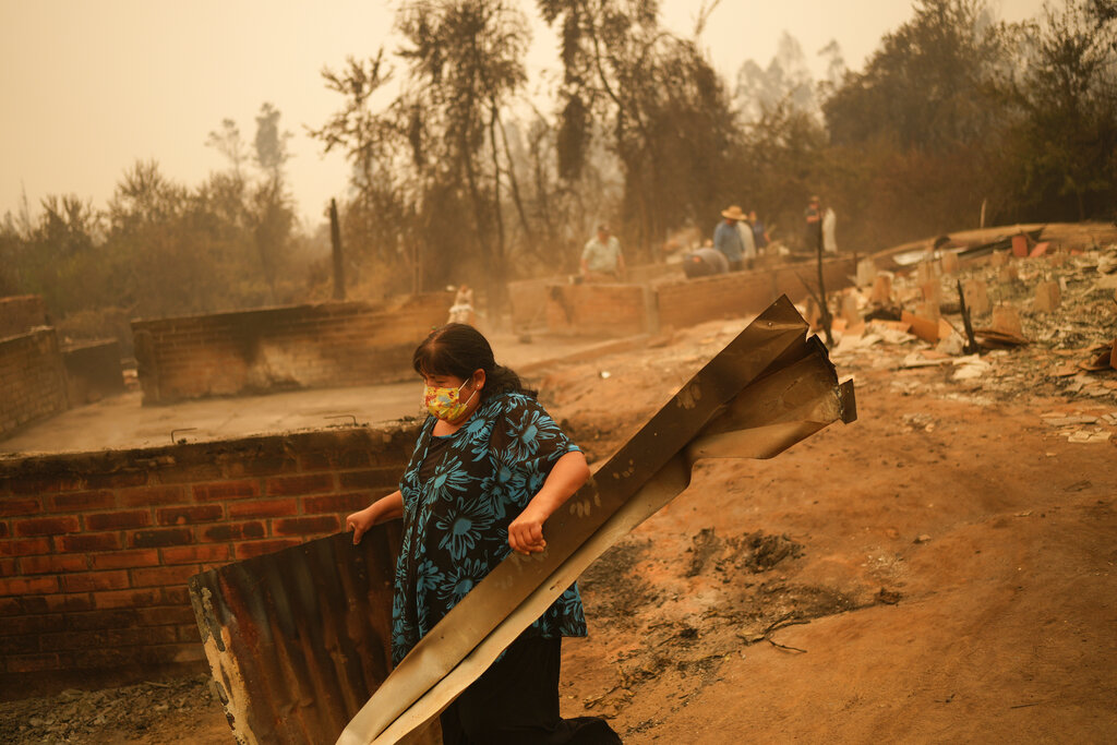 Una mujer remueve escombros en un paisaje devastado por el fuego en Santa Ana, Chile, sábado 4 de febrero de 2023. (Foto: AP/Matias Delacroix)