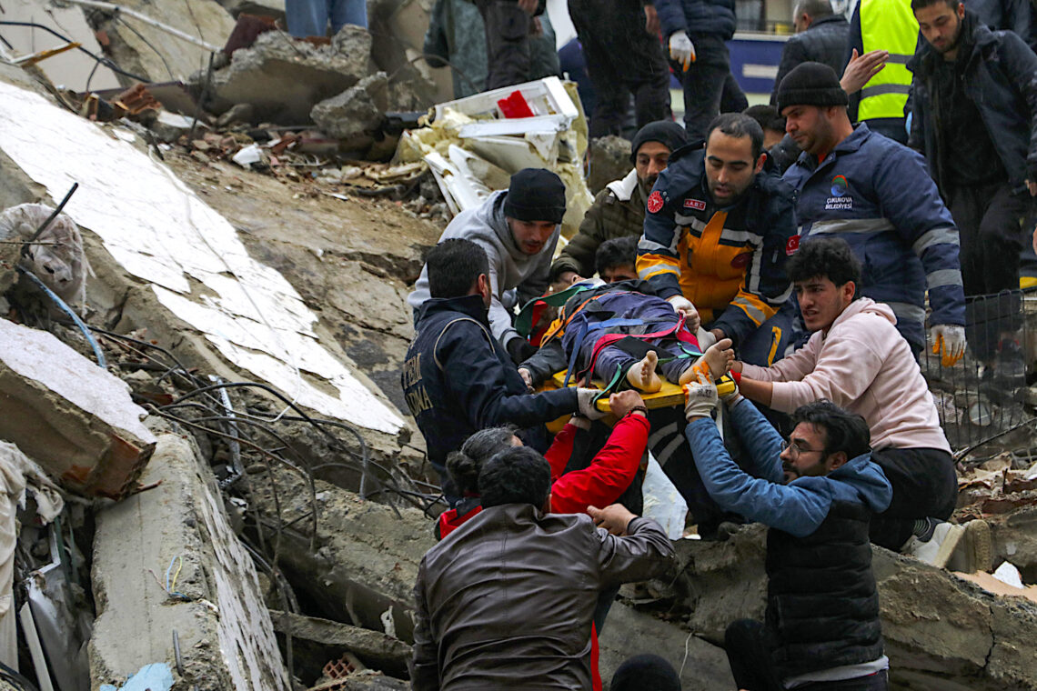 Gente y equipos de rescatistas trasladan a una persona en camilla desde un edificio derruido en Adana, Turquía, el lunes 6 de febrero de 2023. (Foto: IHA agency via AP)
