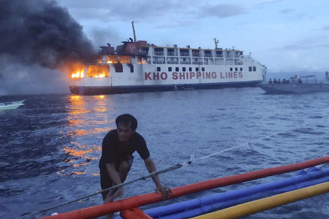 En una imagen proporcionada por la guardia costera de Filipinas, un hombre empuja un bote cerca del ferry filipino M/V Esperanza Star que se incendia en aguas frente a Panglao, en la provincia Bohol, Filiínas. (Foto: Guardia Costera de Filipinas vía AP)