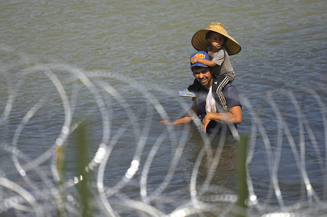 Un migrante cruza el río Bravo con un niño sobre sus hombros en un intento por llegar a Estados Unidos desde México. (Foto: Eric Gay / AP)