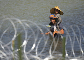 Un migrante cruza el río Bravo con un niño sobre sus hombros en un intento por llegar a Estados Unidos desde México. (Foto: Eric Gay / AP)