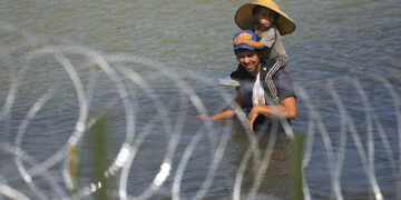 Un migrante cruza el río Bravo con un niño sobre sus hombros en un intento por llegar a Estados Unidos desde México. (Foto: Eric Gay / AP)
