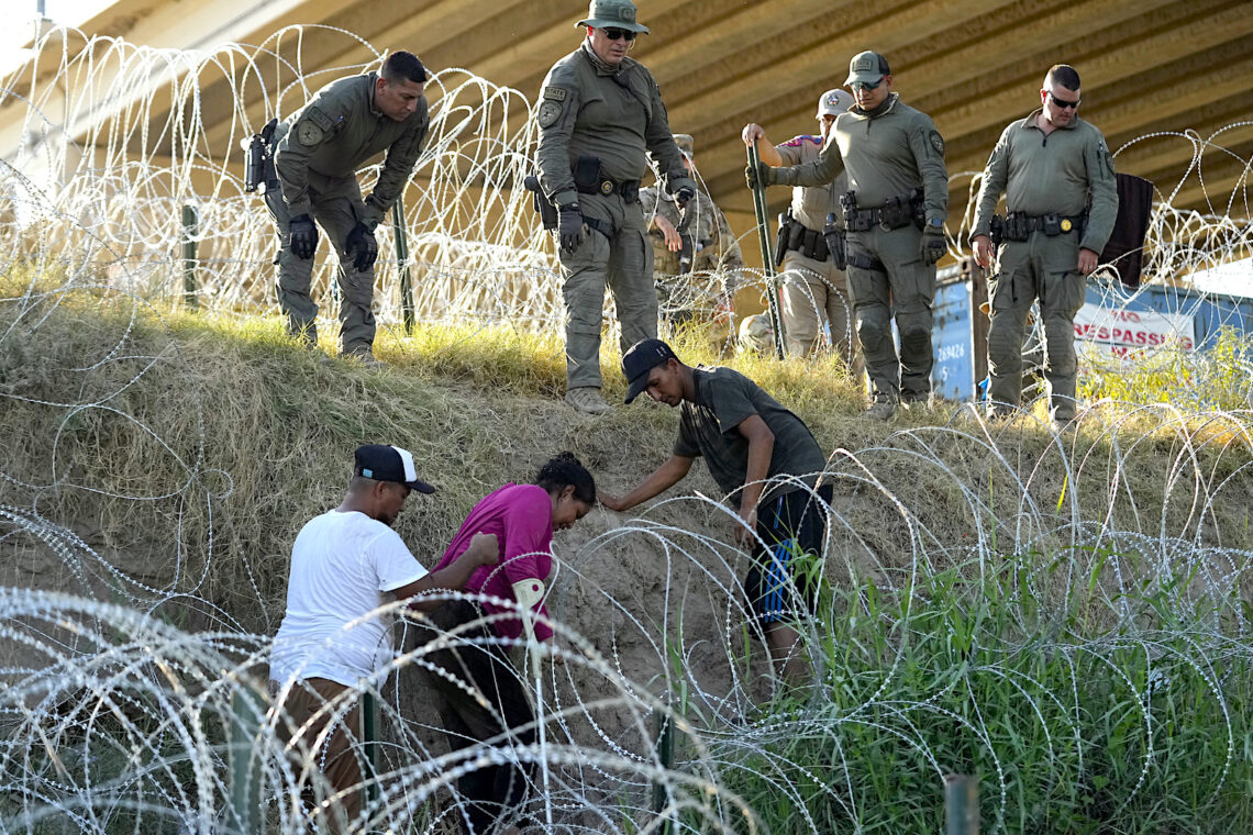Soldados y guardias de Texas ayudan a una migrante que quedó atrapada en un alambre de púas después de cruzar el Río Grande desde México hacia EEUU, en Eagle Pass, Texas. (Foto: Eric Gay / Ap)