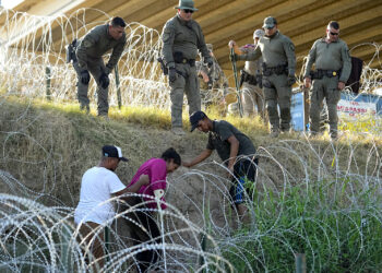 Soldados y guardias de Texas ayudan a una migrante que quedó atrapada en un alambre de púas después de cruzar el Río Grande desde México hacia EEUU, en Eagle Pass, Texas. (Foto: Eric Gay / Ap)