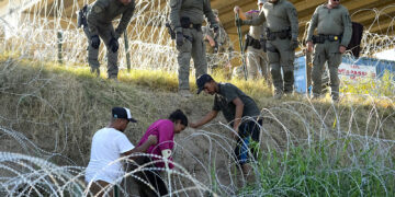 Soldados y guardias de Texas ayudan a una migrante que quedó atrapada en un alambre de púas después de cruzar el Río Grande desde México hacia EEUU, en Eagle Pass, Texas. (Foto: Eric Gay / Ap)