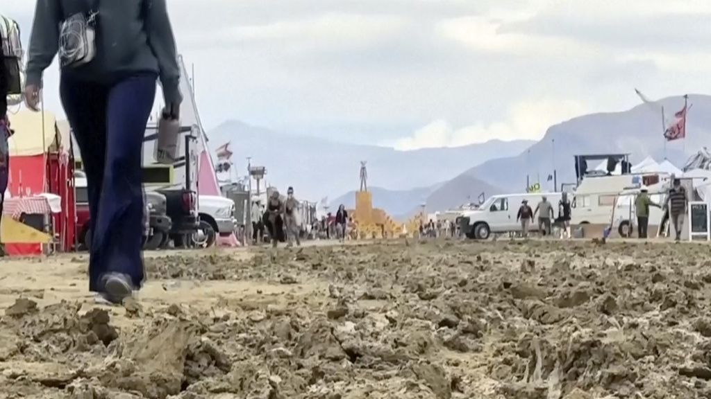 En una imagen tomada de un video proporcionado por Rebecca Barger, varias personas caminan entre el lodo en la sede del festival contracultural Burning Man en Black Rock, Nevada, el lunes 4 de septiembre de 2023. (Rebecca Barger/@rebeccabargerphoto vía AP)