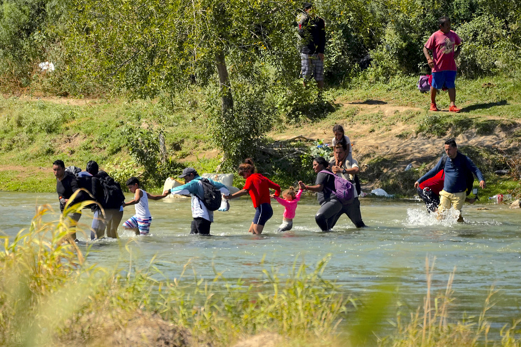 Migrantes cruzan de la mano el río Bravo desde México a Estados Unidos, en Eagle Pass, Texas. (Foto: Eric Gay / AP)