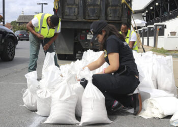 Nicole Torres ata sacos de arena mientras residentes se preparan para la llegada de una tormenta en Annapolis, Maryland. (Foto: Brian Witte / AP)