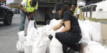 Nicole Torres ata sacos de arena mientras residentes se preparan para la llegada de una tormenta en Annapolis, Maryland. (Foto: Brian Witte / AP)