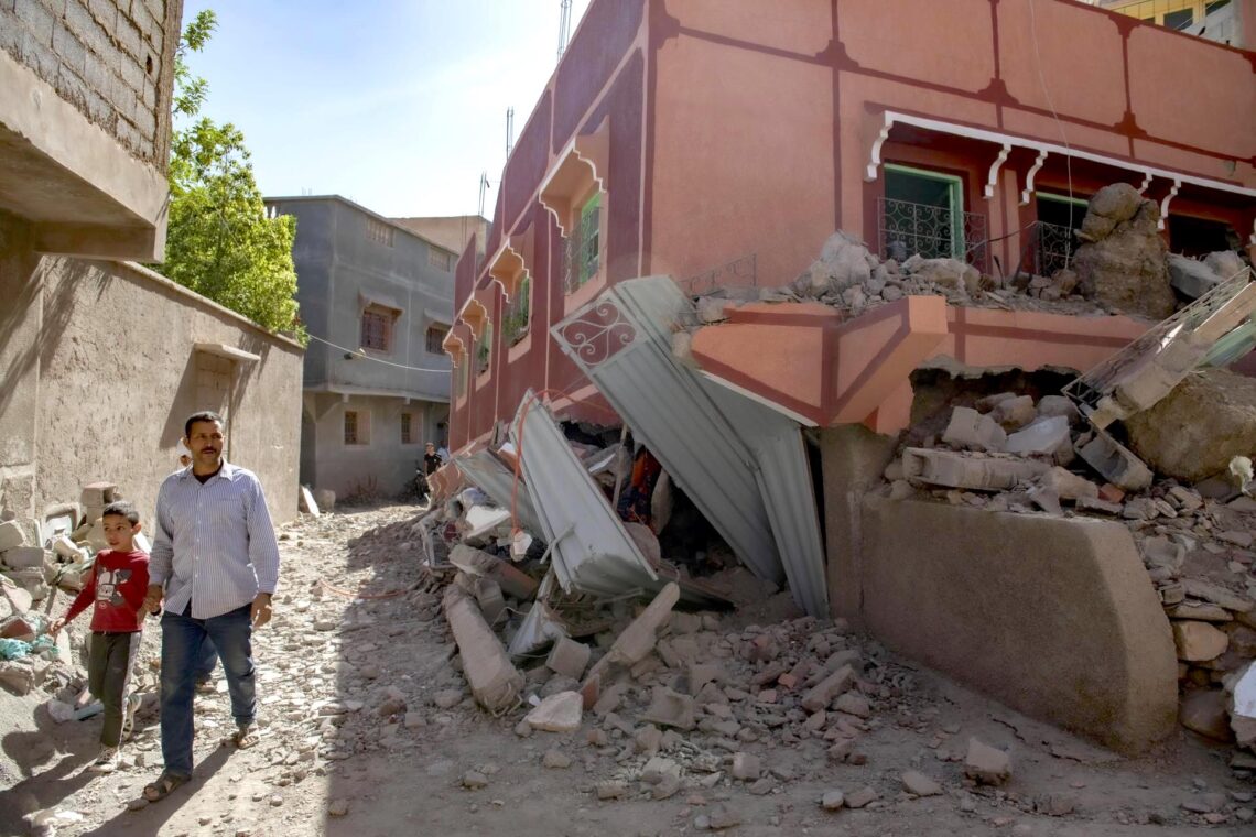 Una persona con un niño camina junto a un edificio dañado tras un terremoto en Marrakech, Marruecos. (Foto: EFE / Jalal Morchidi)
