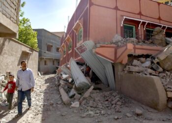 Una persona con un niño camina junto a un edificio dañado tras un terremoto en Marrakech, Marruecos. (Foto: EFE / Jalal Morchidi)