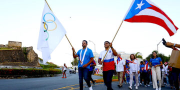 El abanderado para los Juegos Panamericanos Santiago 2023, Jean Pizarro, y el abanderado de los juegos anteriores, Franklin Gomez, caminan junto a los miembros de la delegación de Puerto Rico desde el Comité Olímpico hasta la Fortaleza. (Foto: Thais Llorca / EFE)