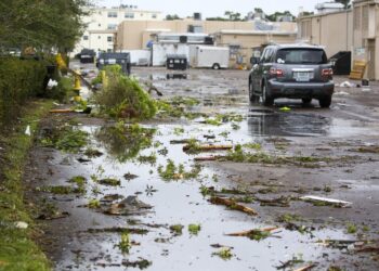 Escombros cubren una playa de estacionamiento en el centro comercial Causeway Plaza en Dunedin, Florida, jueves 12 de octubre de 2023. (Douglas R. Clifford/Tampa Bay Times via AP)