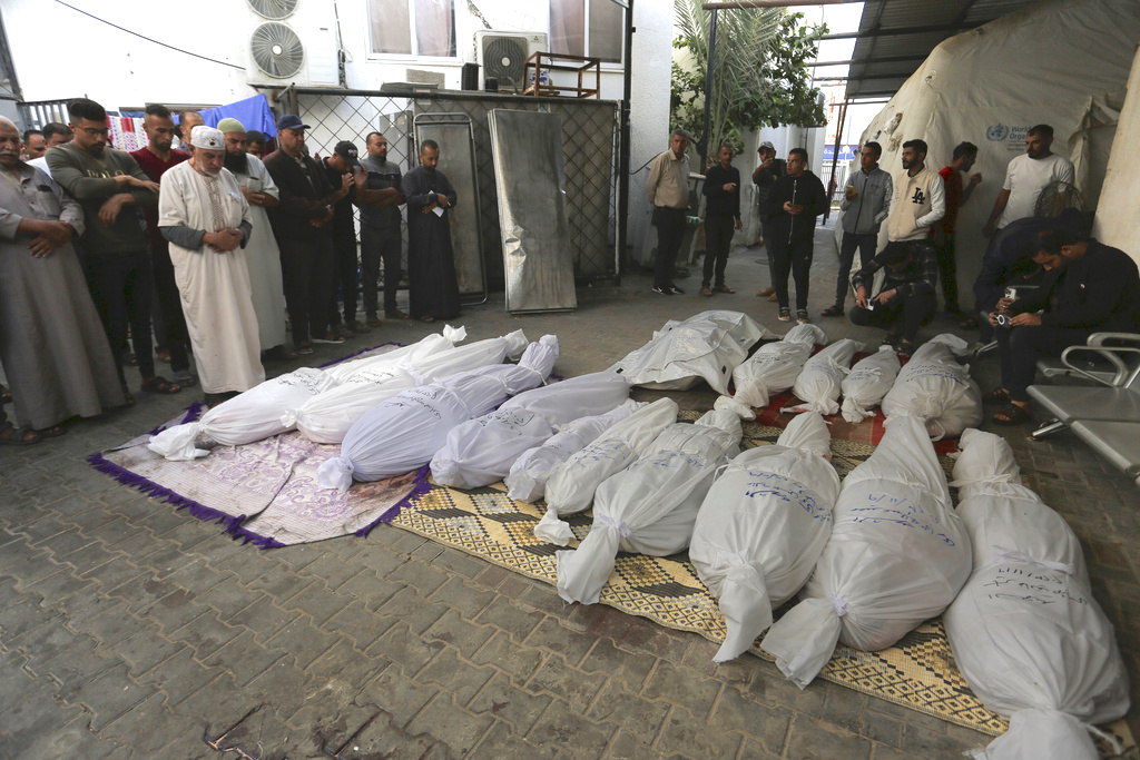 Palestinos rezan junto a los cadáveres de los miembros de la familia Hijazi que murieron en un bombardeo israelí en Rafah. (Foto: Hatem Ali / AP)
