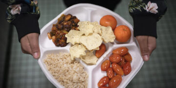 Una alumna de séptimo grado lleva su plato vegano, el cual consiste de chili con frijoles, arroz, mandarinas, tomates cereza y papitas horneadas, en el distrito de Brooklyn, Nueva York. (Foto: AP/Wong Maye-E, archivo)
