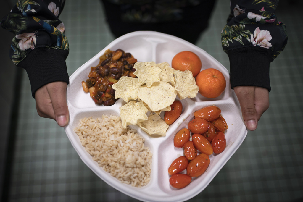 Una alumna de séptimo grado lleva su plato vegano, el cual consiste de chili con frijoles, arroz, mandarinas, tomates cereza y papitas horneadas, en el distrito de Brooklyn, Nueva York. (Foto: AP/Wong Maye-E, archivo)