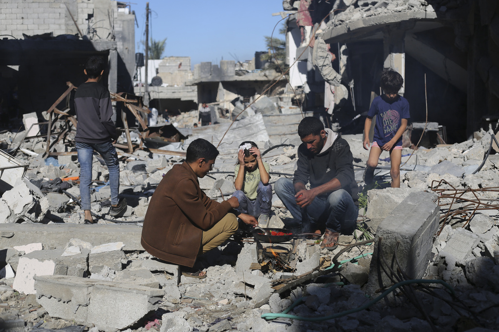 Palestinos cuecen pan junto a sus casas destruidas en Kuza' a, en la Franja de Gaza, durante el cese el fuego temporal entre Hamás e Israel, el miércoles 29 de noviembre de 2023.  (Foto: AP/Hatem Ali)