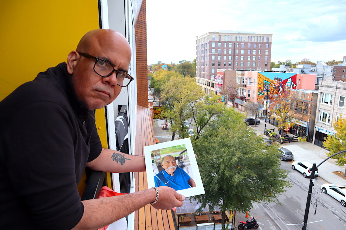 Elías Carmona Rivera sostiene la foto de su padre, Elías Carmona Alejandro, en el balcón de su apartamento en el barrio puertorriqueño de Chicago. Elías y su hermana Sandra son un ejemplo de los retos que enfrentan muchos hijos a cargo de cuidar a sus padres envejecidos, tanto en Puerto Rico como desde la diáspora. (Foto: Vanesa Baerga)