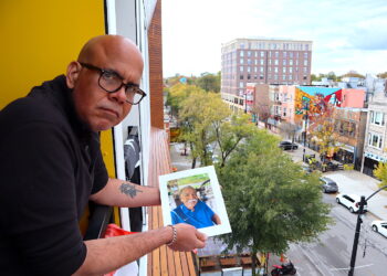 Elías Carmona Rivera sostiene la foto de su padre, Elías Carmona Alejandro, en el balcón de su apartamento en el barrio puertorriqueño de Chicago. Elías y su hermana Sandra son un ejemplo de los retos que enfrentan muchos hijos a cargo de cuidar a sus padres envejecidos, tanto en Puerto Rico como desde la diáspora. (Foto: Vanesa Baerga)