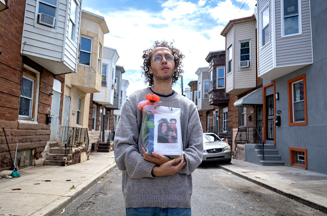 Guillermo Santos sostiene la urna con las cenizas de su padre en la calle, frente a la casa donde se crió en el barrio de Kensington, en Filadelfia. Su papá, nacido en Puerto Rico, murió de una sobredosis. (Foto: Solmaira Valerio / CPI)