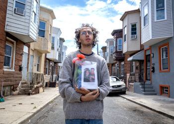 Guillermo Santos sostiene la urna con las cenizas de su padre en la calle, frente a la casa donde se crió en el barrio de Kensington, en Filadelfia. Su papá, nacido en Puerto Rico, murió de una sobredosis. (Foto: Solmaira Valerio / CPI)